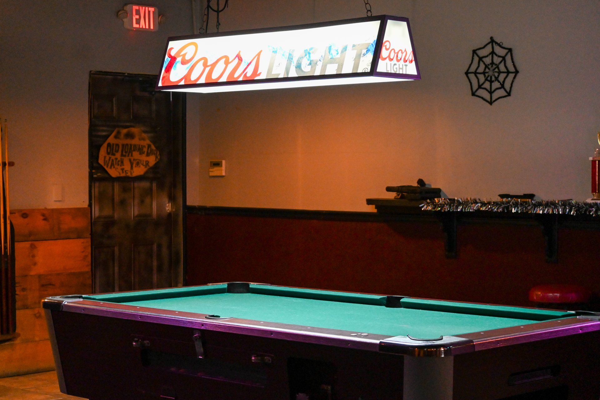 A pool table with a coors light sign above it