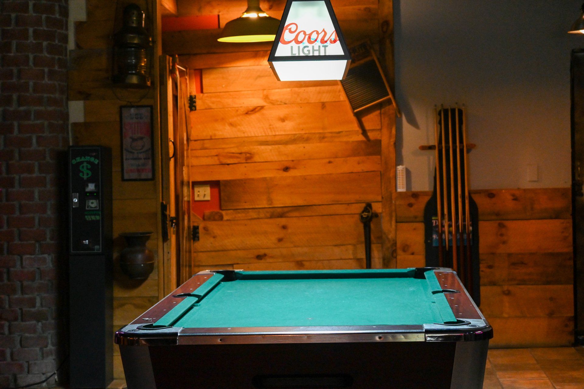 A pool table with a coors light sign above it