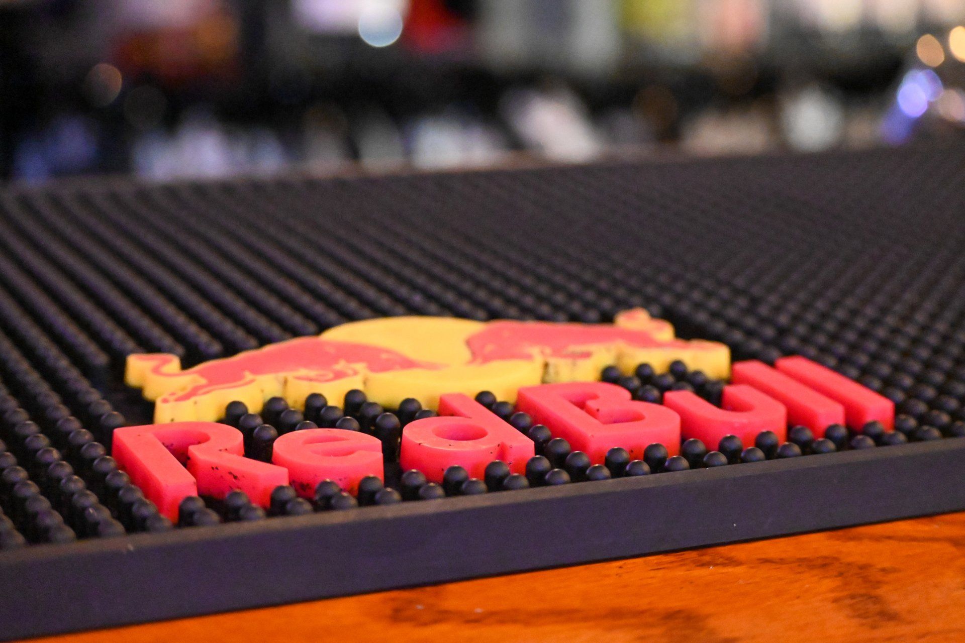 A red bull bar mat is sitting on top of a wooden bar.