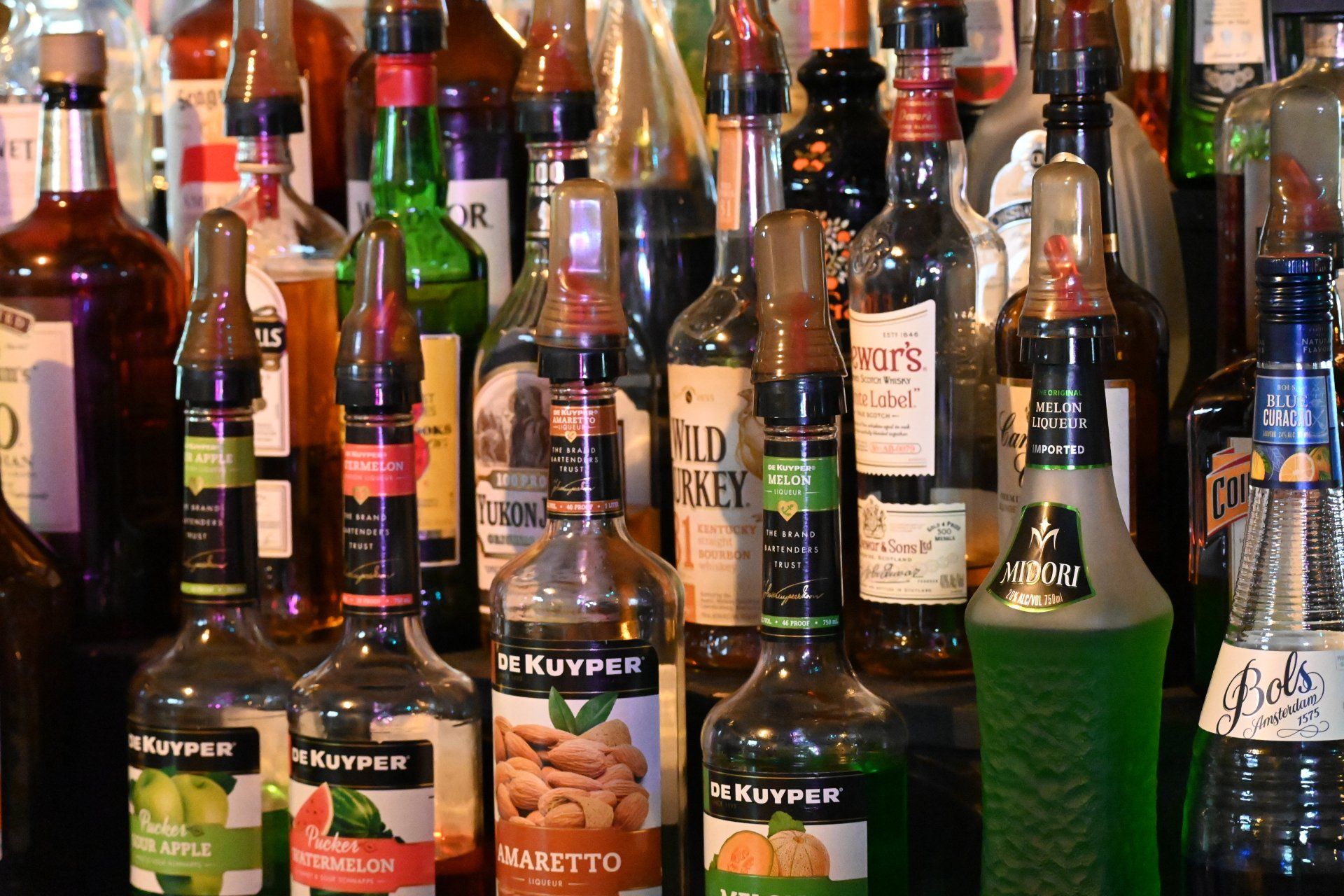 A bunch of bottles of liquor are lined up on a bar