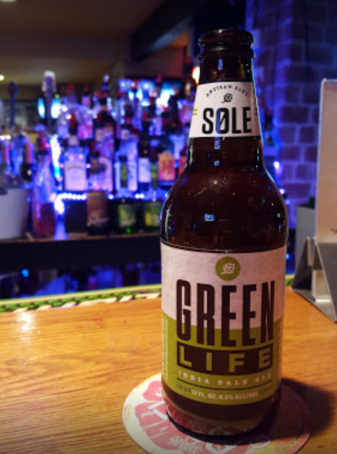 A bottle of sole green life sits on a bar