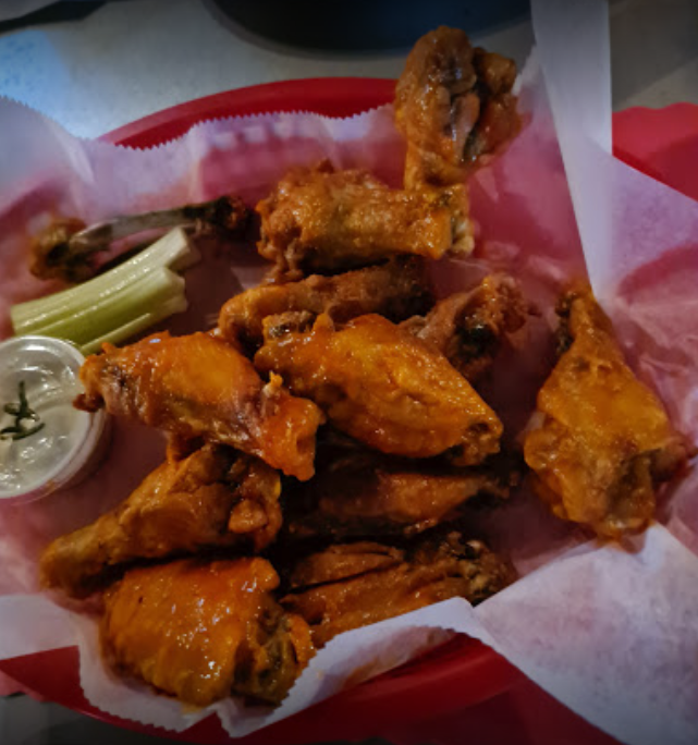 A basket of chicken wings with celery and ranch dressing
