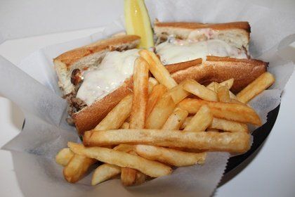 A sandwich and french fries in a basket on a table.