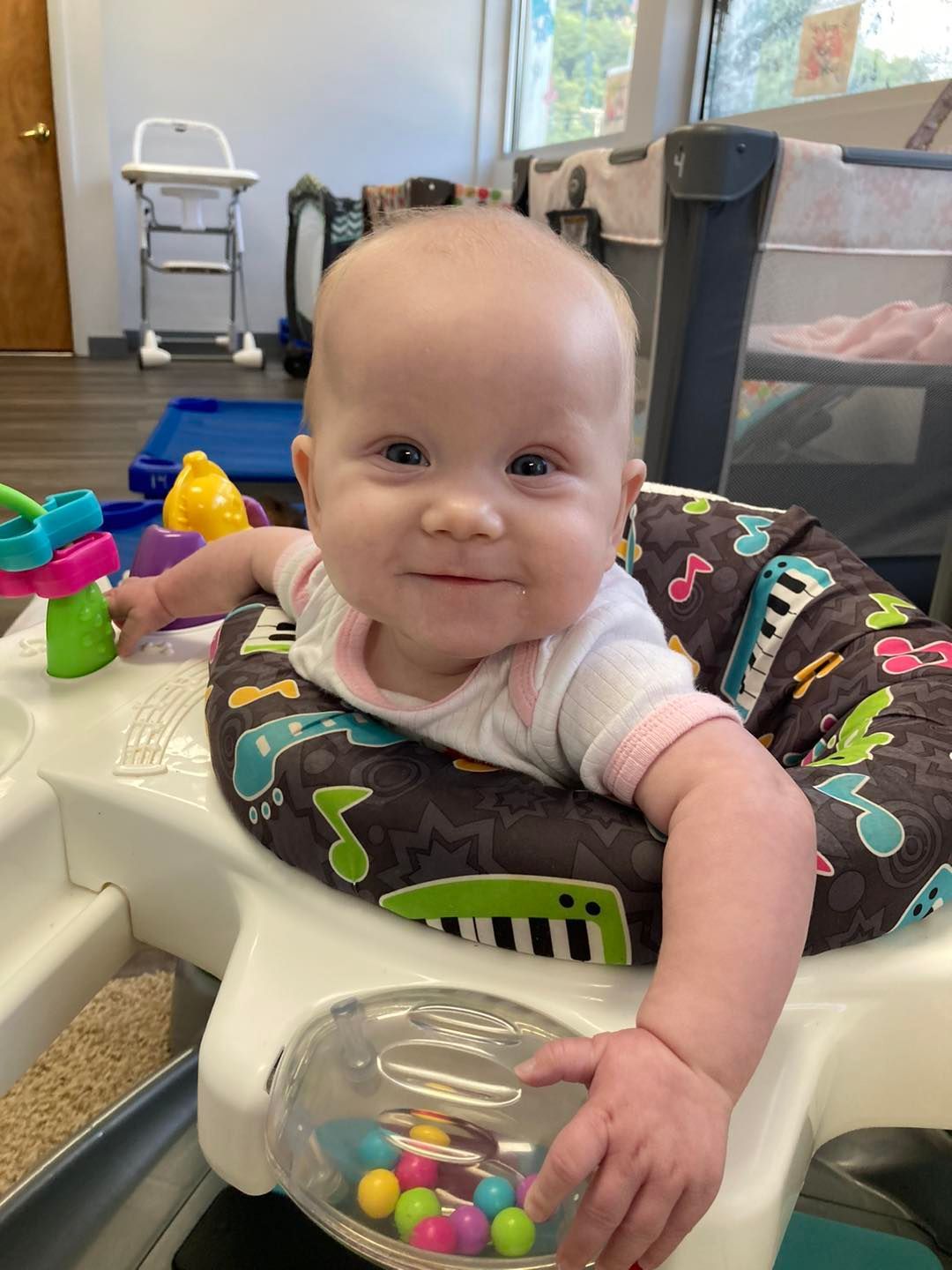 A baby is sitting in a high chair holding a toy.