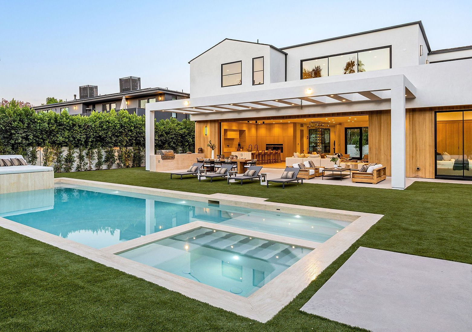 Modern home exterior with pool and backyard lounge area.