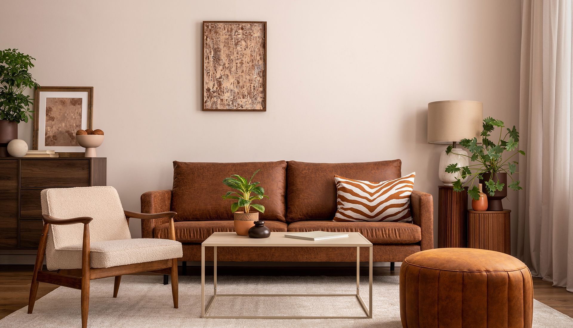 Living room with brown leather sofa, tan armchair, coffee table, and plants.