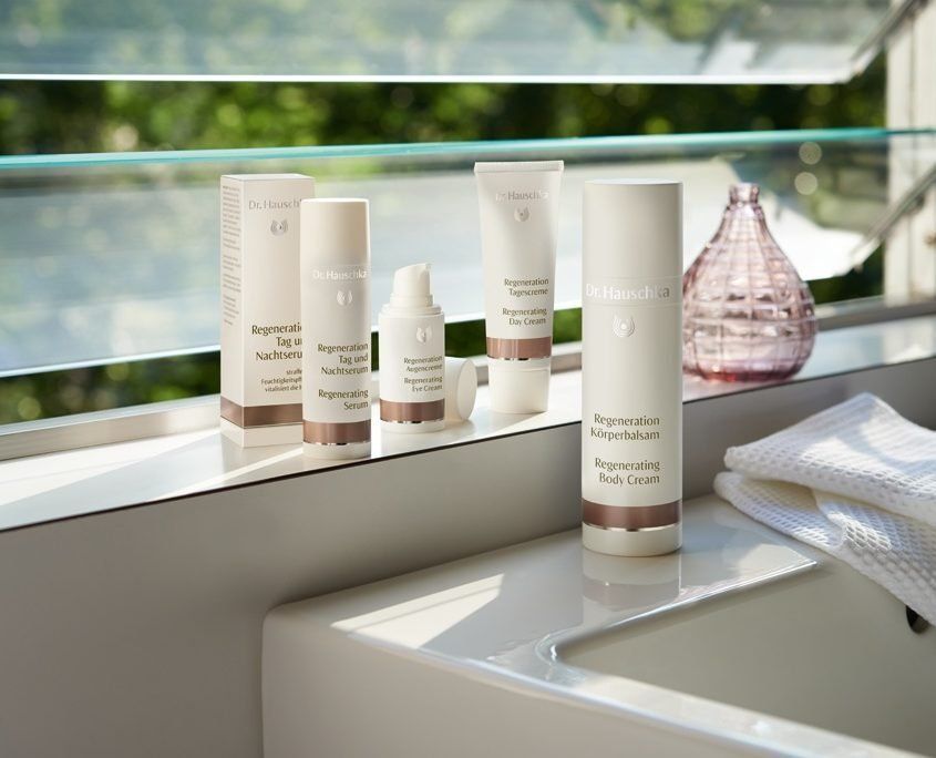 Auf einer Theke neben einem Fenster stehen mehrere Flaschen Kosmetikartikel.