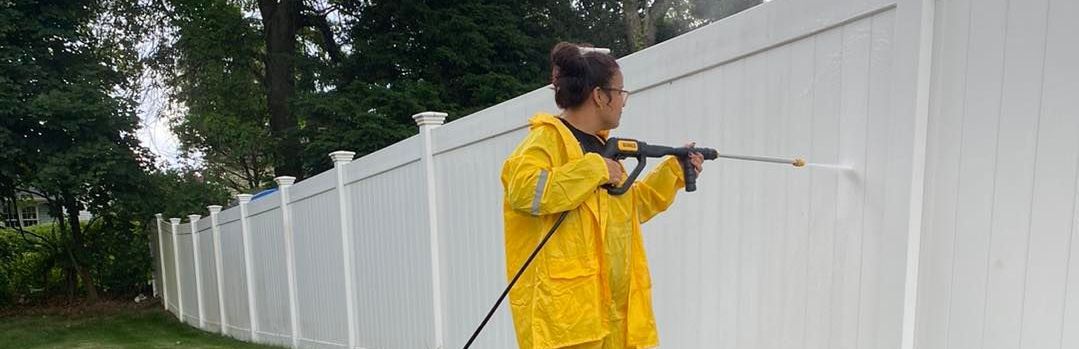 A man is standing on a ladder painting a garage door.