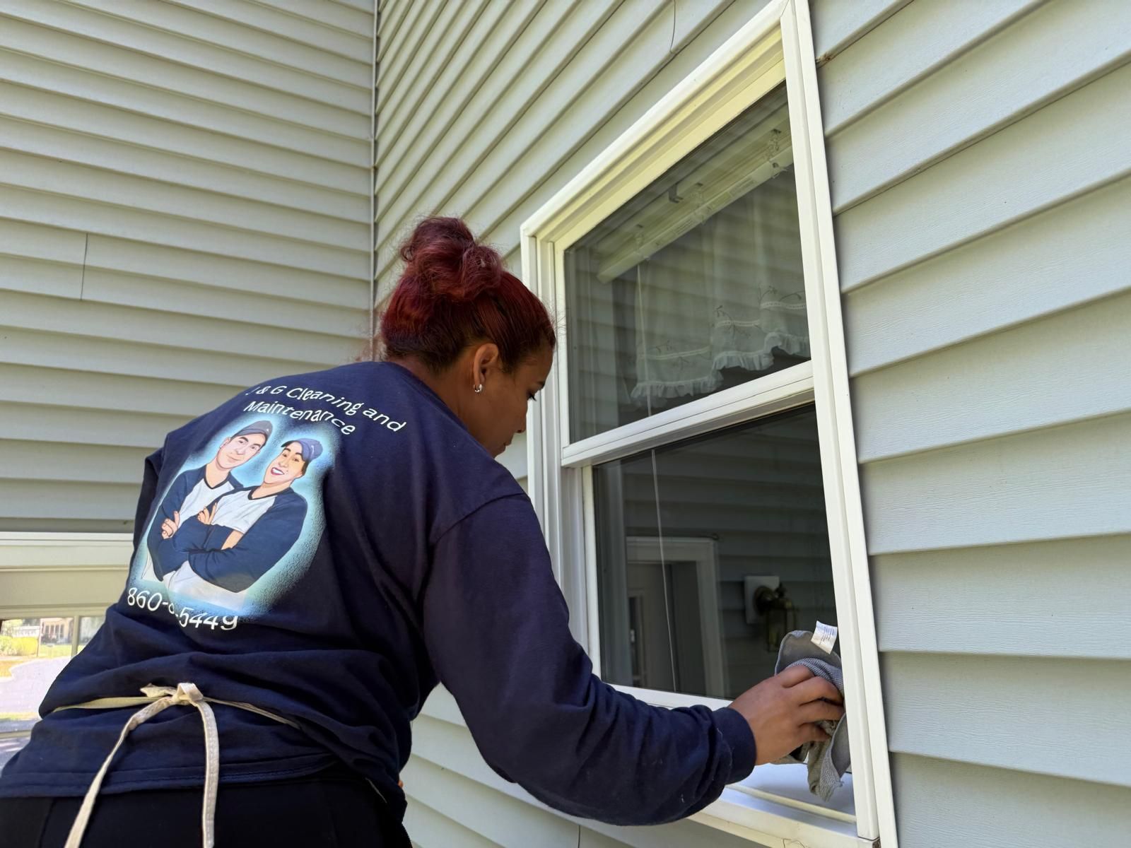 A man is standing on a ladder painting a garage door.