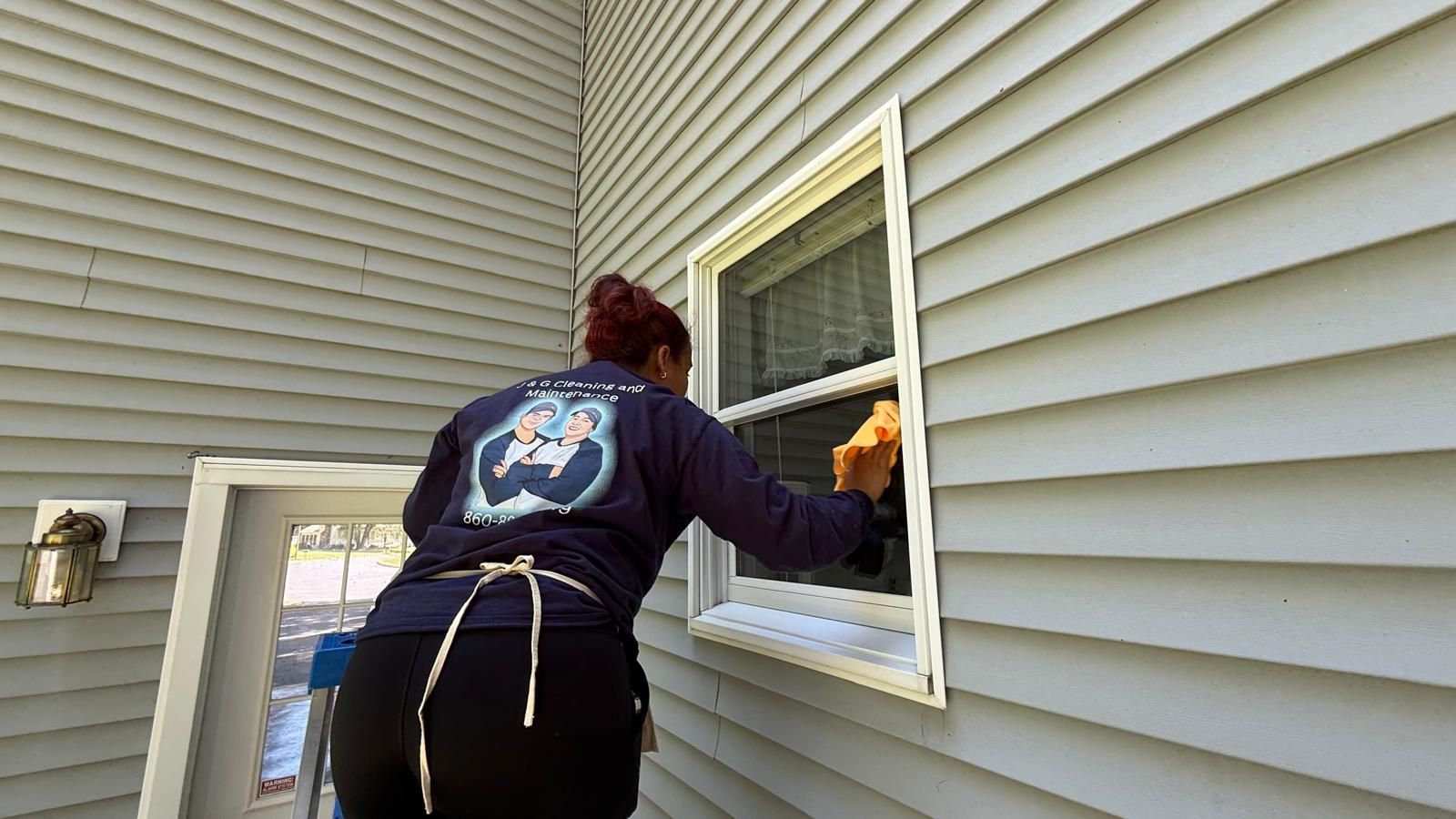 A man is standing on a ladder painting a garage door.