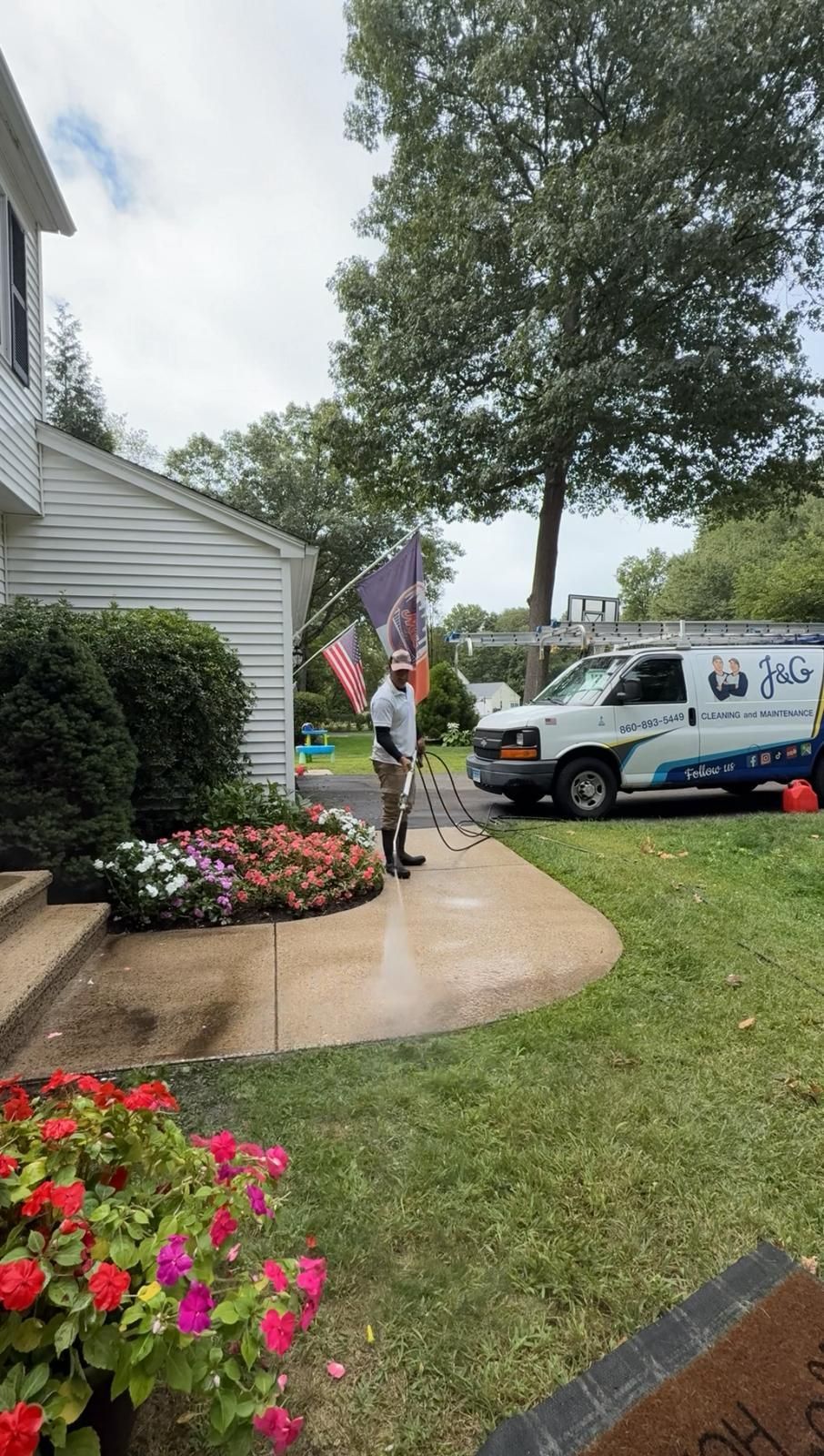 A man is standing on a ladder painting a garage door.