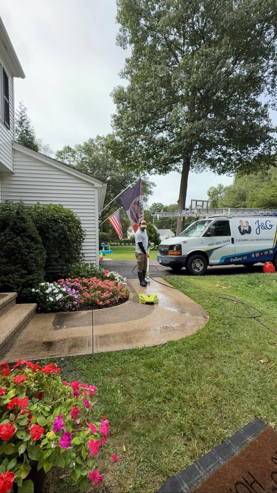 A man is standing on a ladder painting a garage door.
