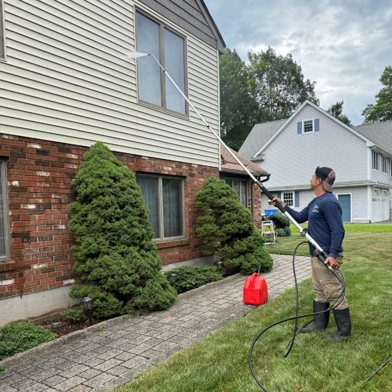 A man is standing on a ladder painting a garage door.