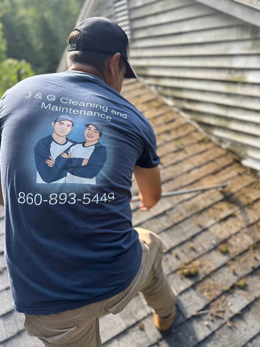 Technician sweeping moss and debris during roof cleaning in New Britain CT