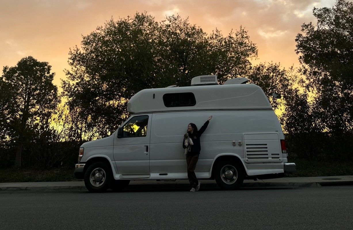 Ottillie holding Roman in front of Roman’s Empire’s custom mobile grooming van in Folsom, California.