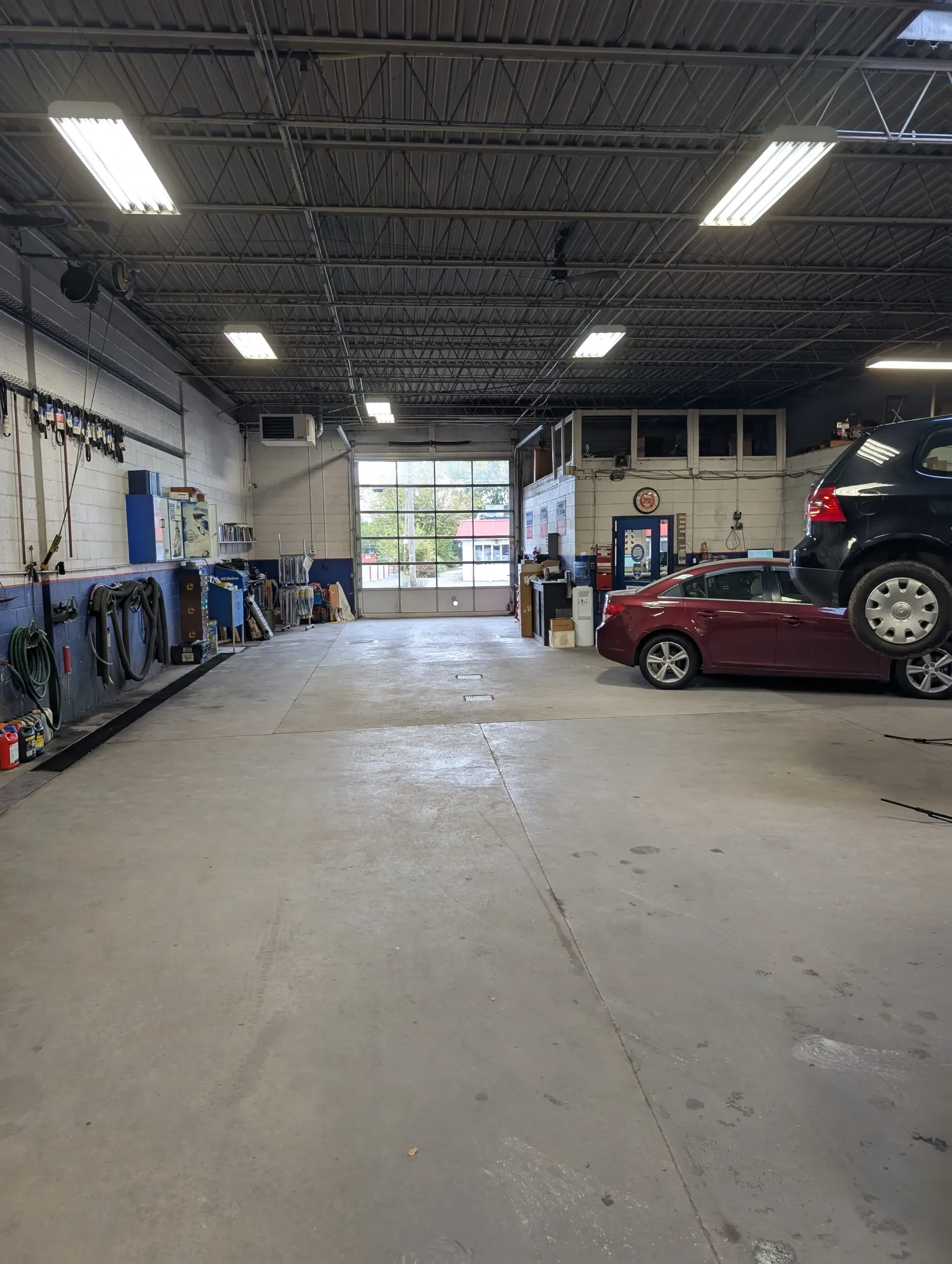 Interior of an auto repair shop with two cars, one on a lift | Rymer Automotive