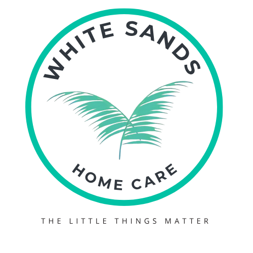The logo for white sands home care shows a heart with two hands inside of it.