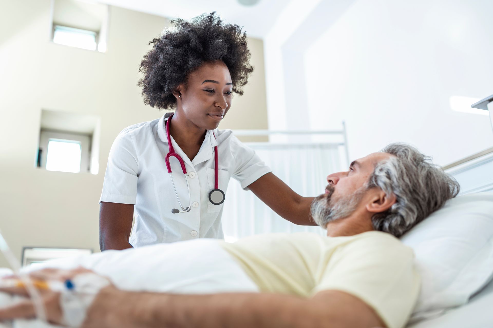 A nurse is talking to a patient in a hospital bed.
