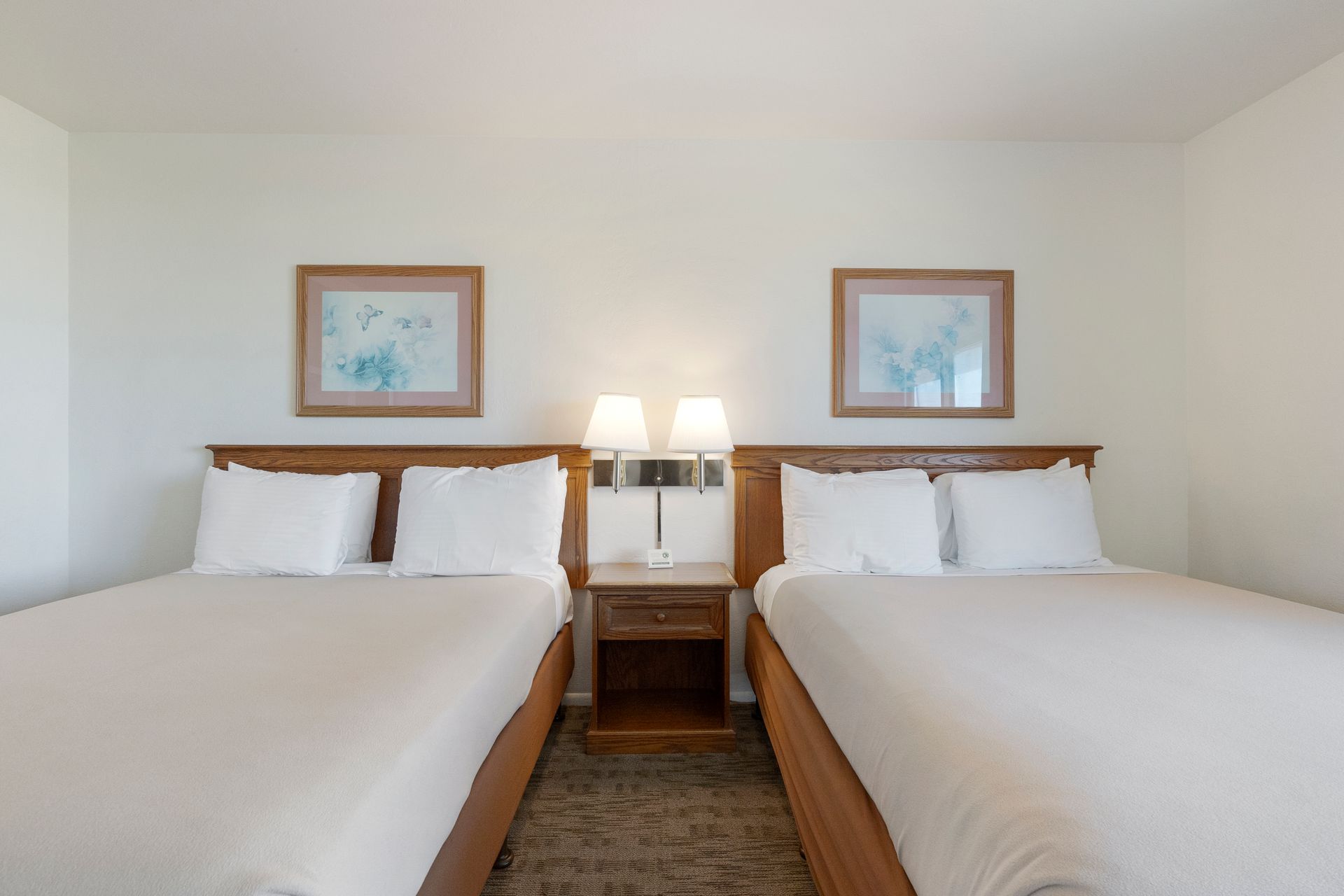 Two beds in a hotel room with matching artwork.