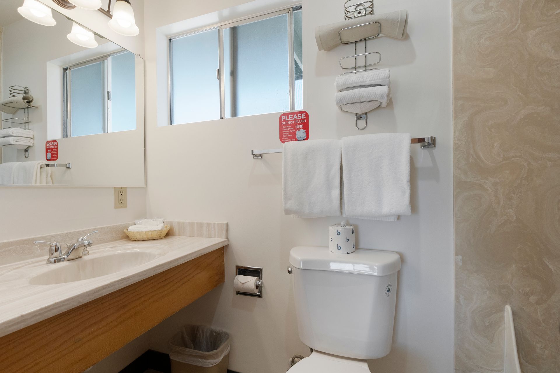 Bathroom with a sink, toilet, and towels. A window is above the toilet.