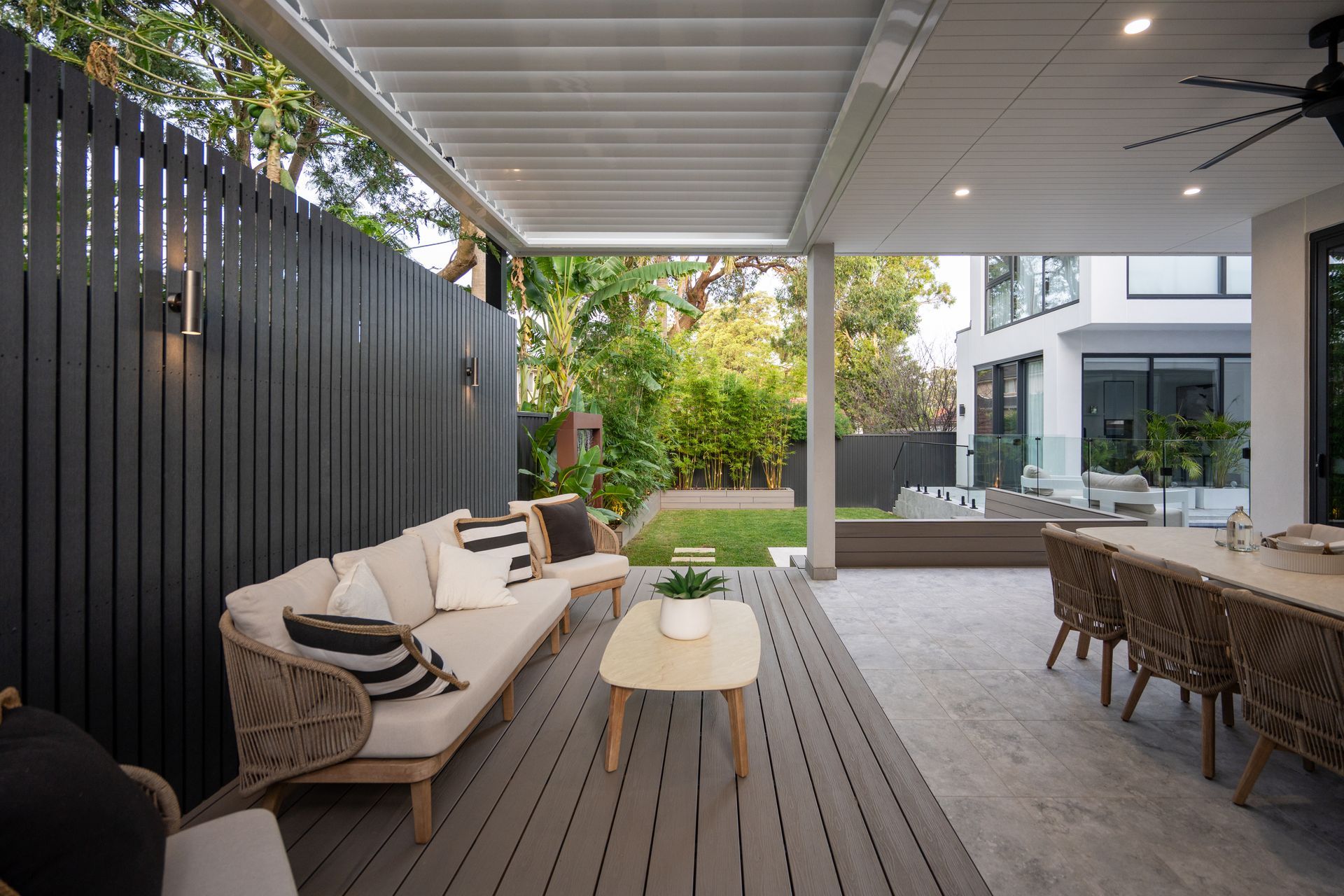 A patio with a couch , table , chairs and a ceiling fan.