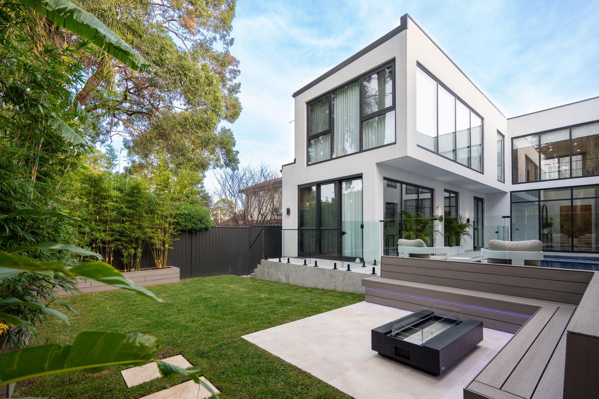A large white house with a lot of windows and a fire pit in the backyard.