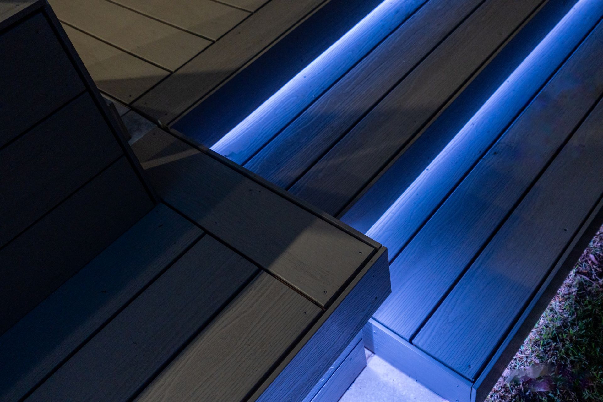 A wooden deck with blue lights on the steps.