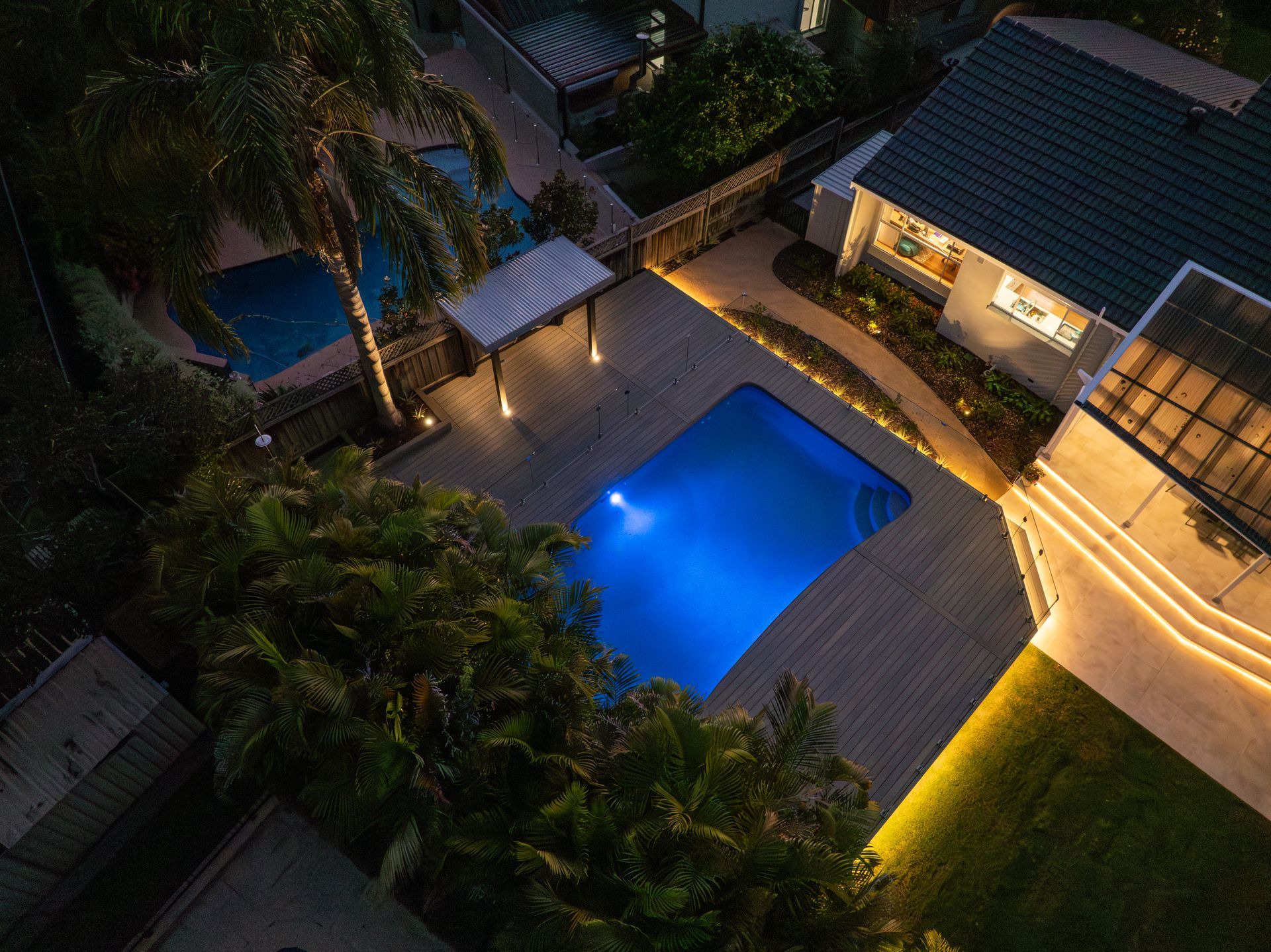 An aerial view of a swimming pool in a backyard at night