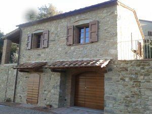 uno stabile di pietra con le porte in legno e due finestre aperte