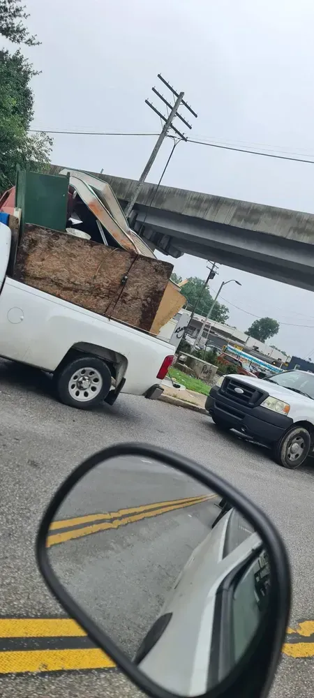 A white pickup truck carrying a load of materials, has struck a utility pole under an overpass.