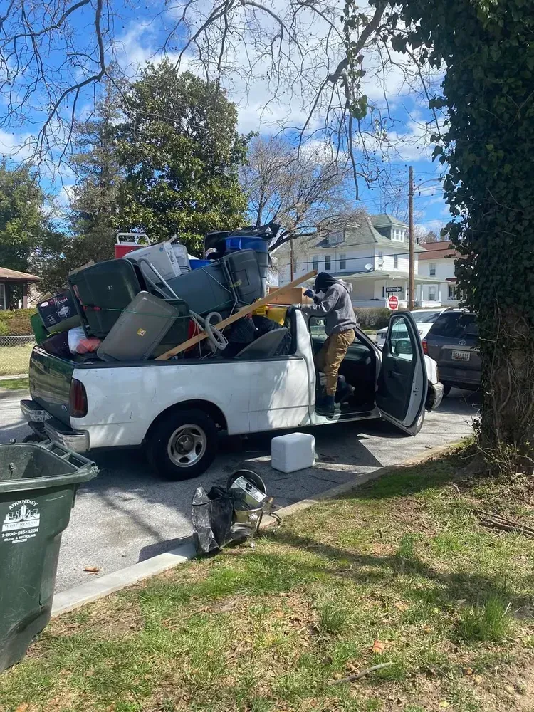 Man loading junk into a white pickup truck parked on a residential street.