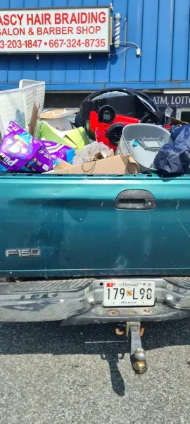 Green pickup truck bed filled with items, license plate