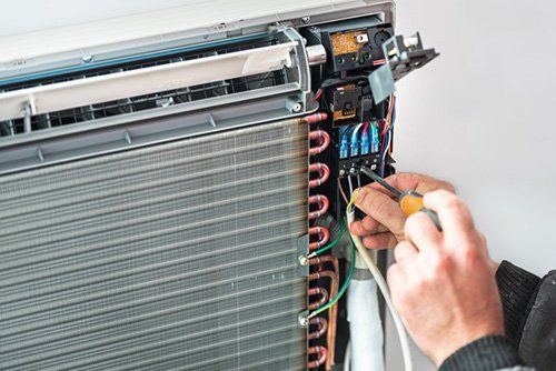 Technician Repairing Electrical Wiring in Air Conditioning Unit