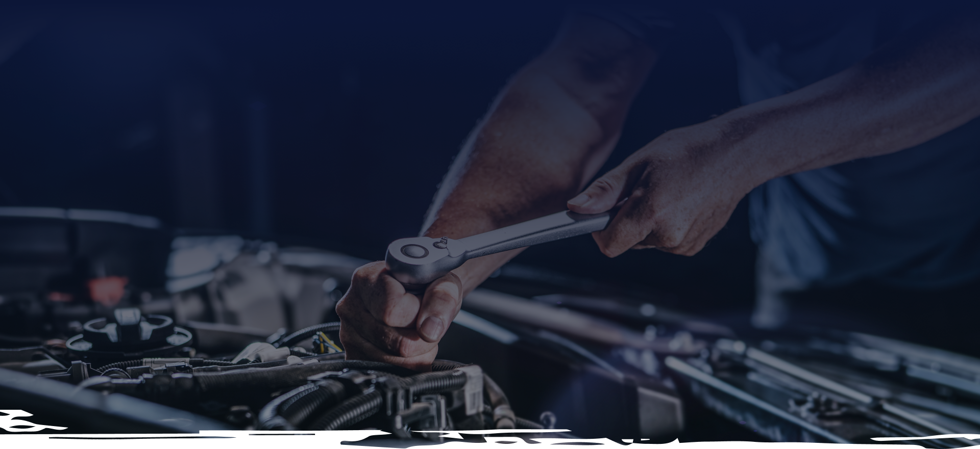 Mechanic using a wrench to repair a car engine in a dimly lit garage. | Do Good Automotive