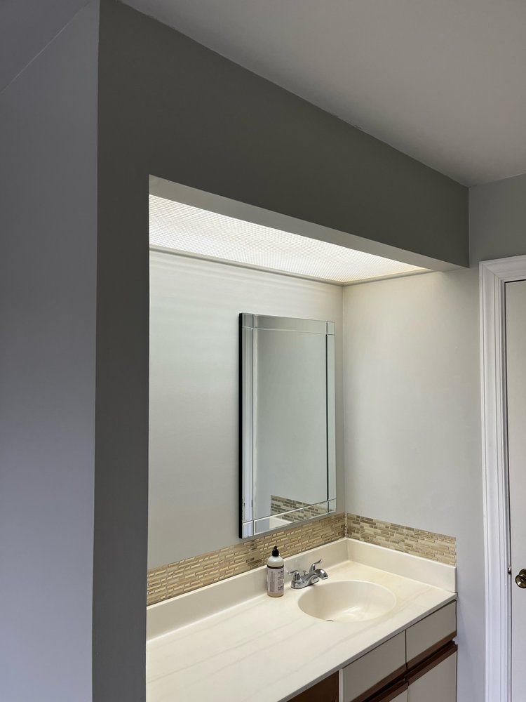 A bathroom with a sink , mirror and vanity.
