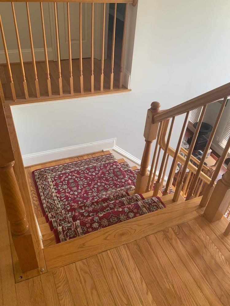 A wooden staircase with a rug on the floor and a wooden railing.