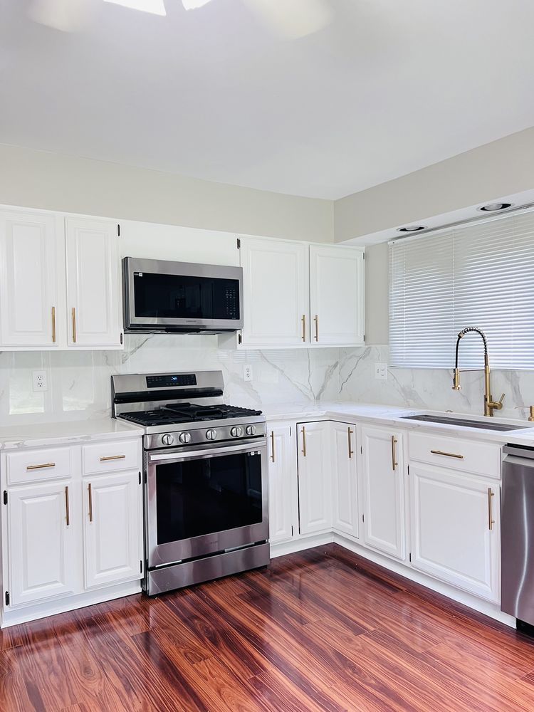 A kitchen with white cabinets , stainless steel appliances , and hardwood floors.