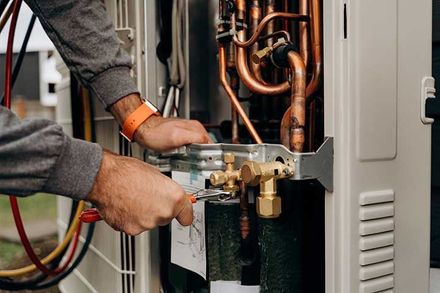 Technician's hands with tools working on the copper pipes of the air conditioner. 