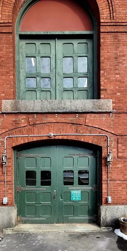 Historic brick building entrance with green doors at Cabot Mill Antiques