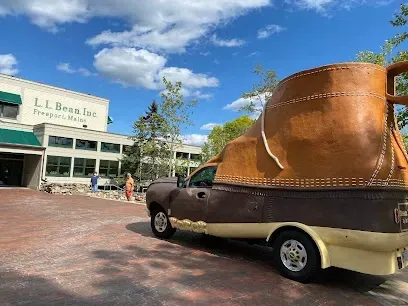 Chimney-Sweep-Portland-A large boot-shaped vehicle is parked in front of the L.L. Bean Inc. store in Freeport, Maine, under a partly cloudy sky, creating a whimsical scene.