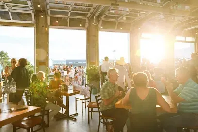Crowd gathered inside Flight Deck Brewing during sunset with indoor seating