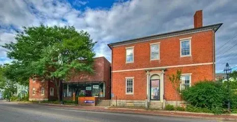 Chimney-Sweep-Portland-Two adjacent brick buildings with large green trees and a cloudy sky.