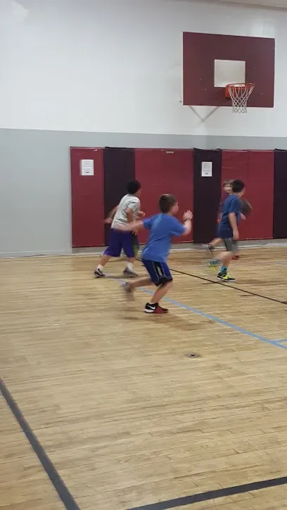 Chimney-Sweep-Portland-Boys play basketball in a gymnasium with a wooden floor and a basketball hoop visible.