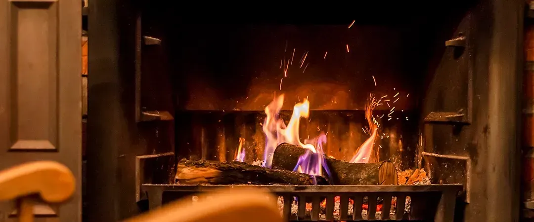 A fireplace with a wooden chair in front of it.