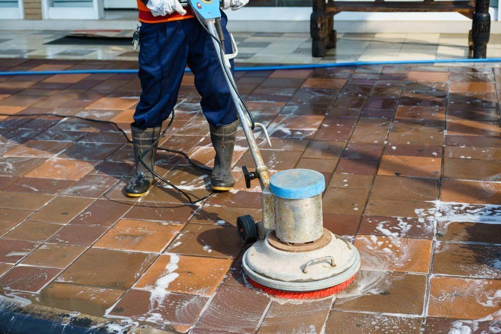 A Man Is Cleaning A Tiled Floor With A Machine — NJP Services In Campbelltown, NSW