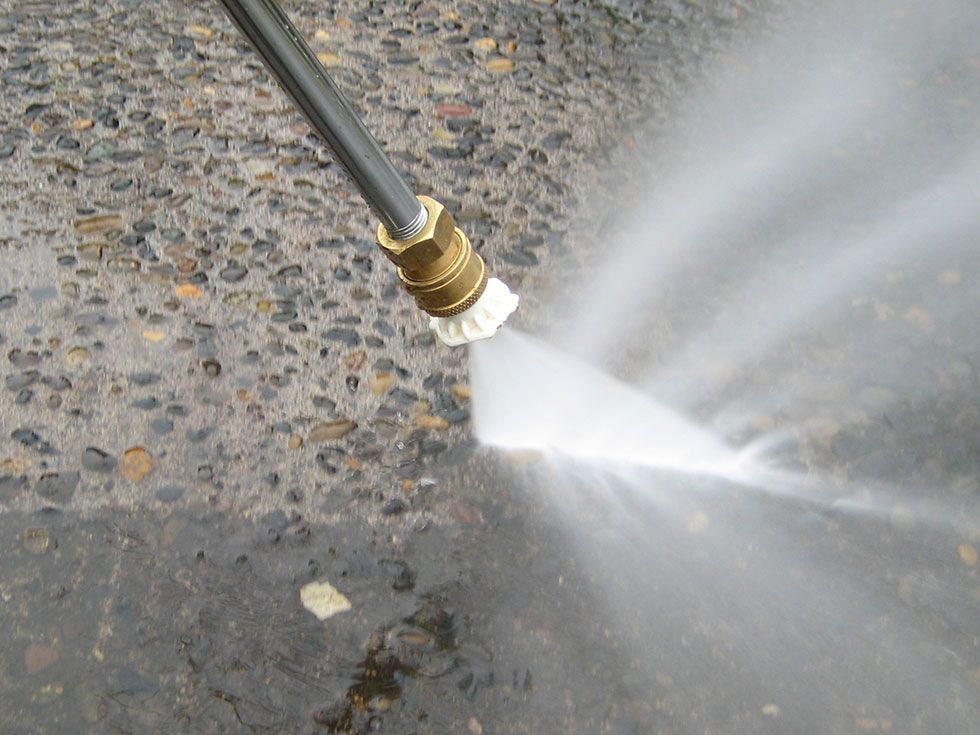 A Man Is Using A High Pressure Washer To Clean A Sidewalk — NJP Services In Coniston, NSW