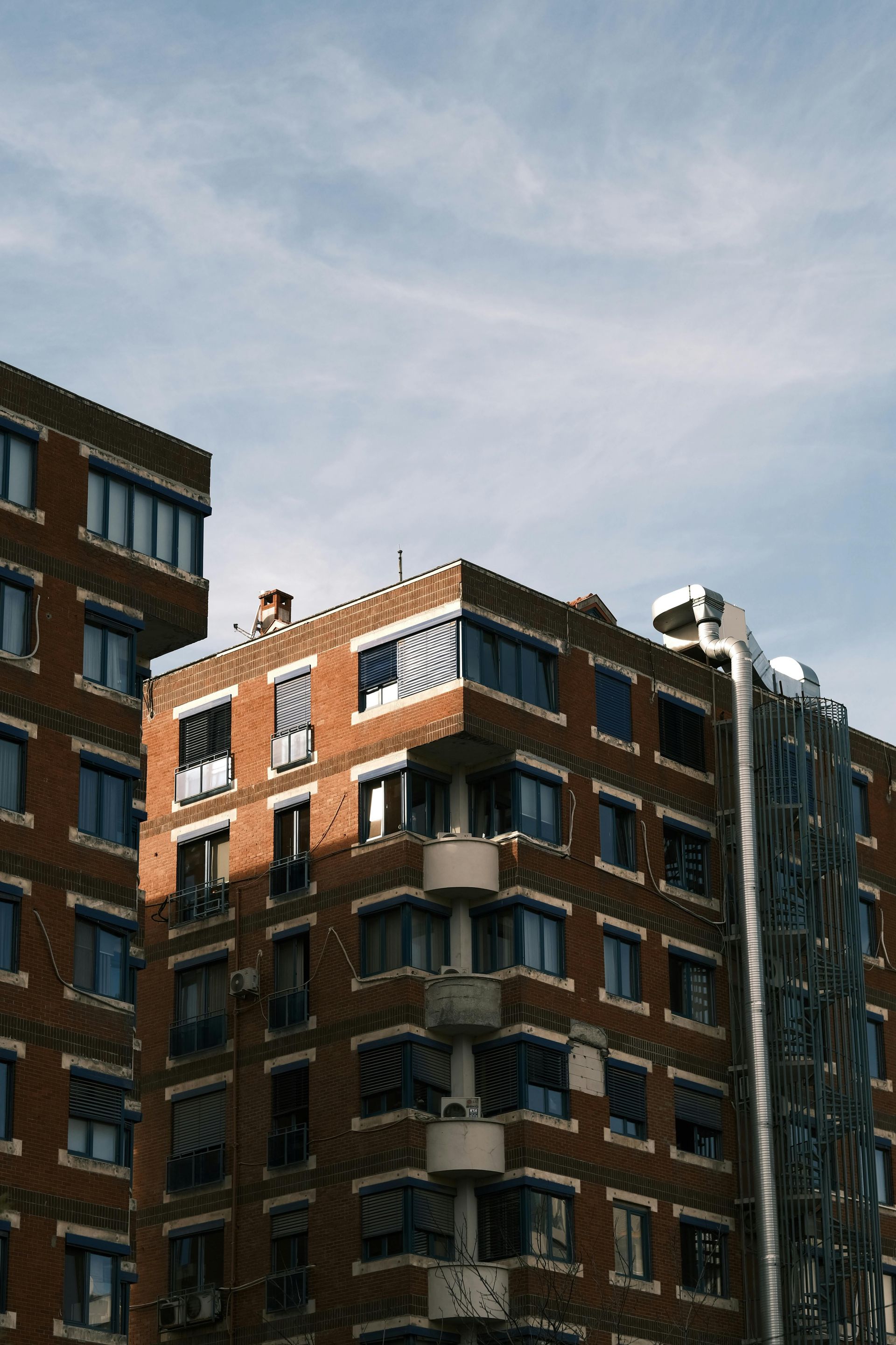 Brick apartment buildings against a blue sky, with sunlight casting shadows.