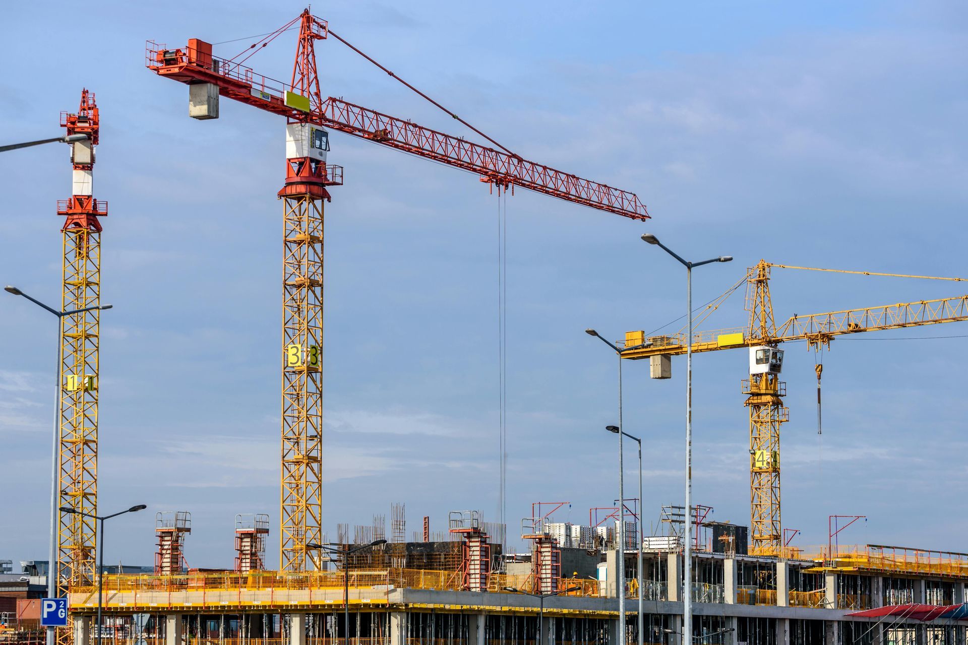 Construction site with multiple cranes lifting materials; buildings under construction.
