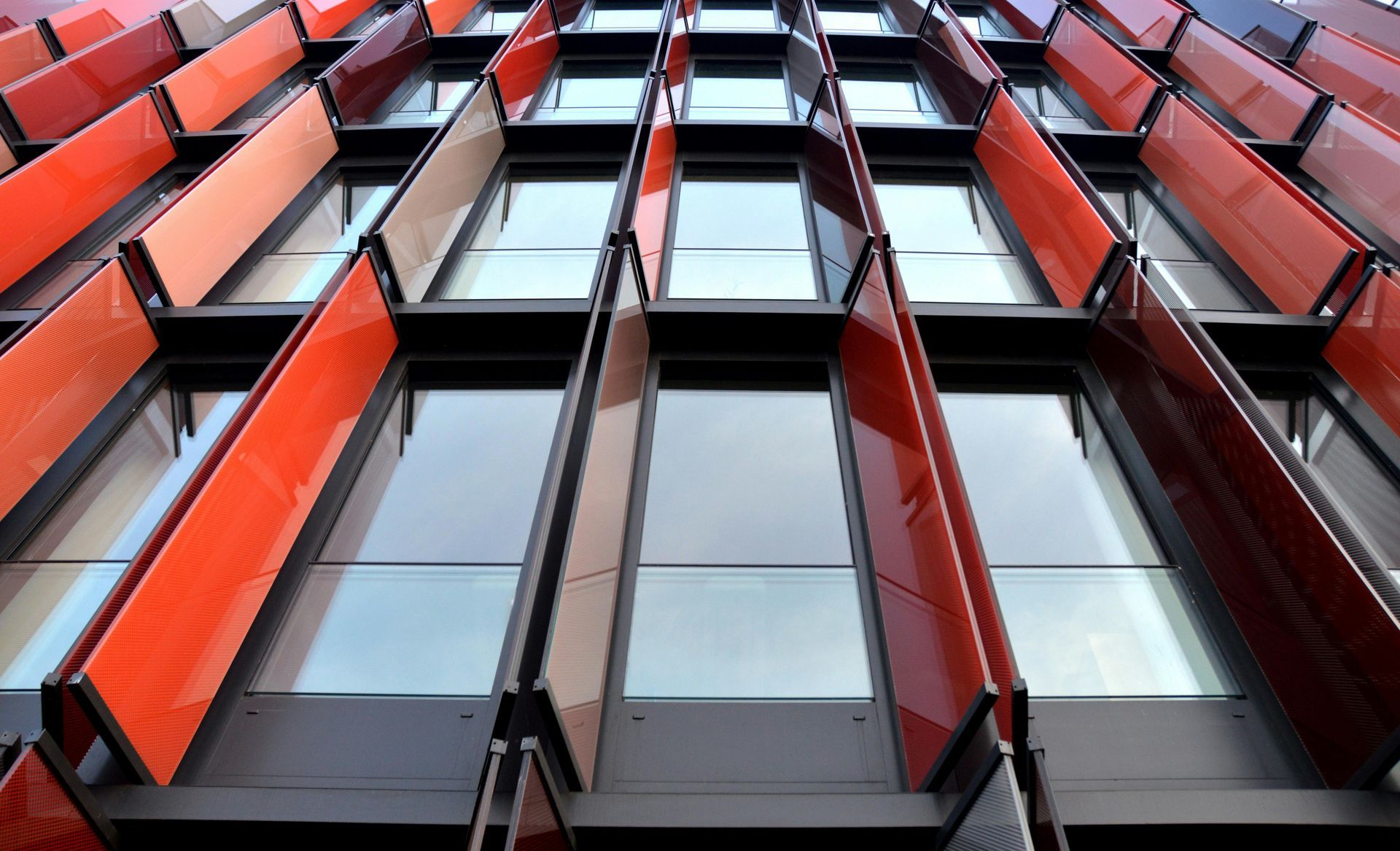 Modern building facade with red and orange angled panels over windows.