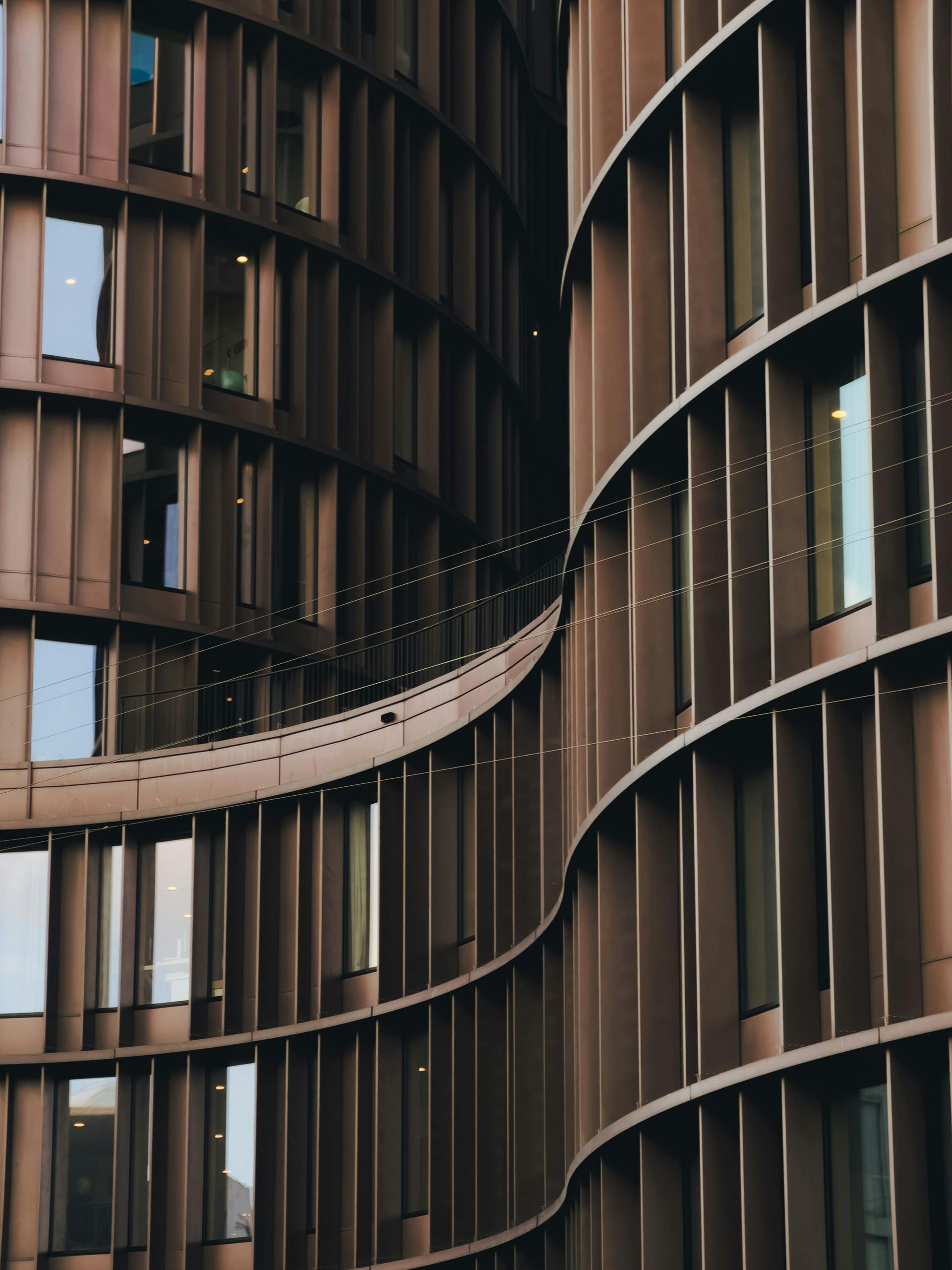 Curved brown building exterior with vertical slats and rectangular windows.